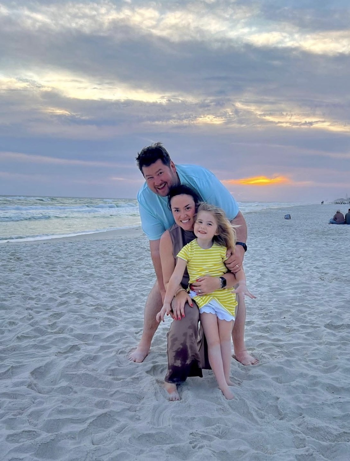 Bryan, Emily, and Clara on the beach at sunset